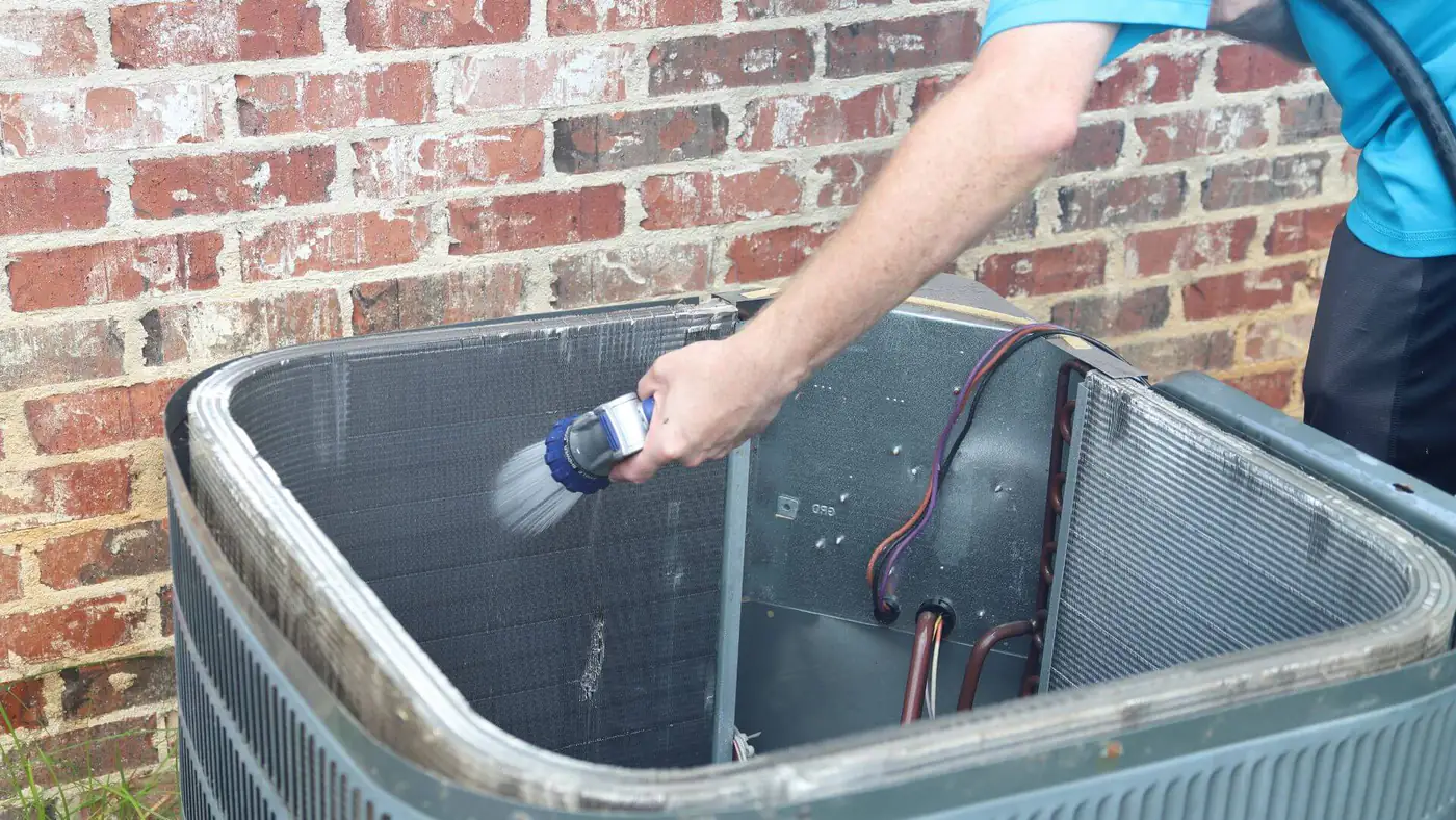 Condenser coil cleaning in Bristol Engineer cleaning the condenser coil of an outdoor air conditioning unit in Bristol