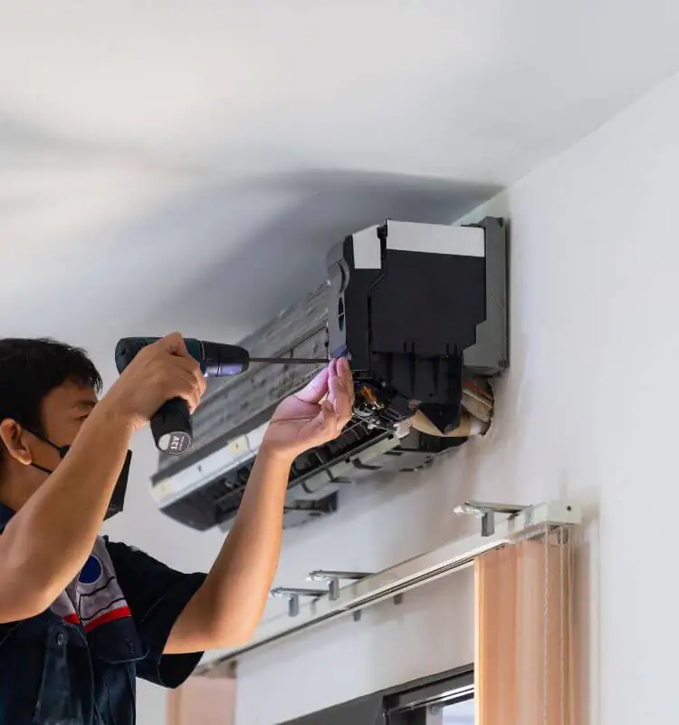 Air conditioning repair in Bristol Engineer repairing the internal parts of a wall-mounted air conditioning unit in Bristol